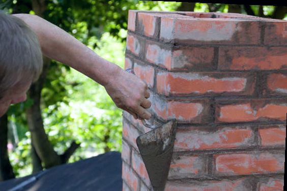 Mason working mortar onto a red brick chimney rebuild in Ocean County